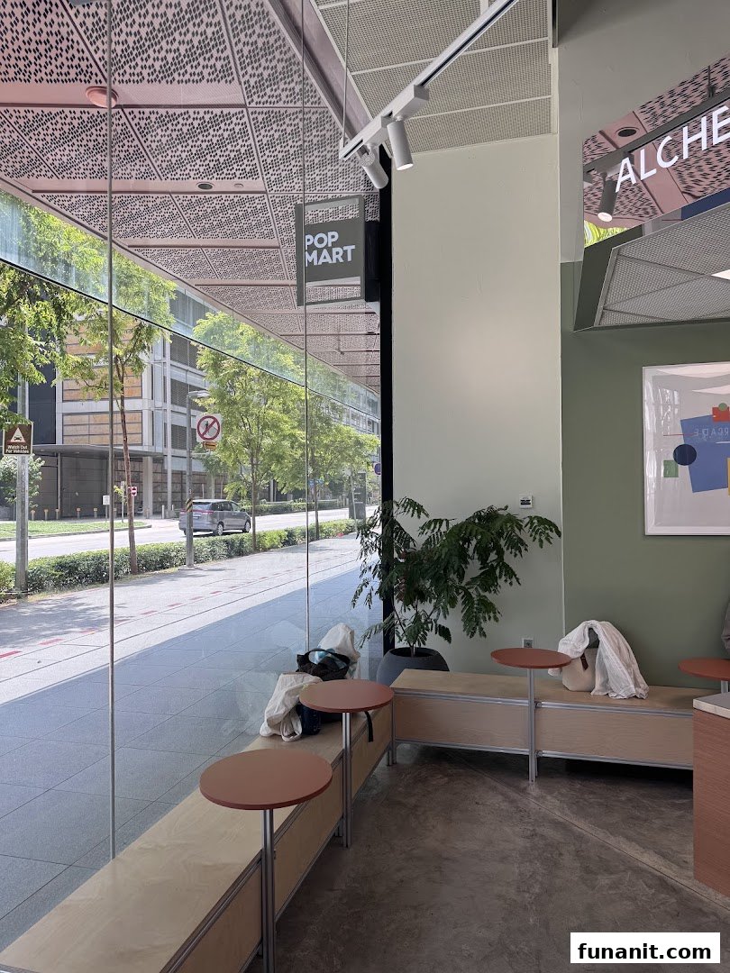 Interior view of Alchemist Funan cafe with large windows, showing seating and a street view outside.