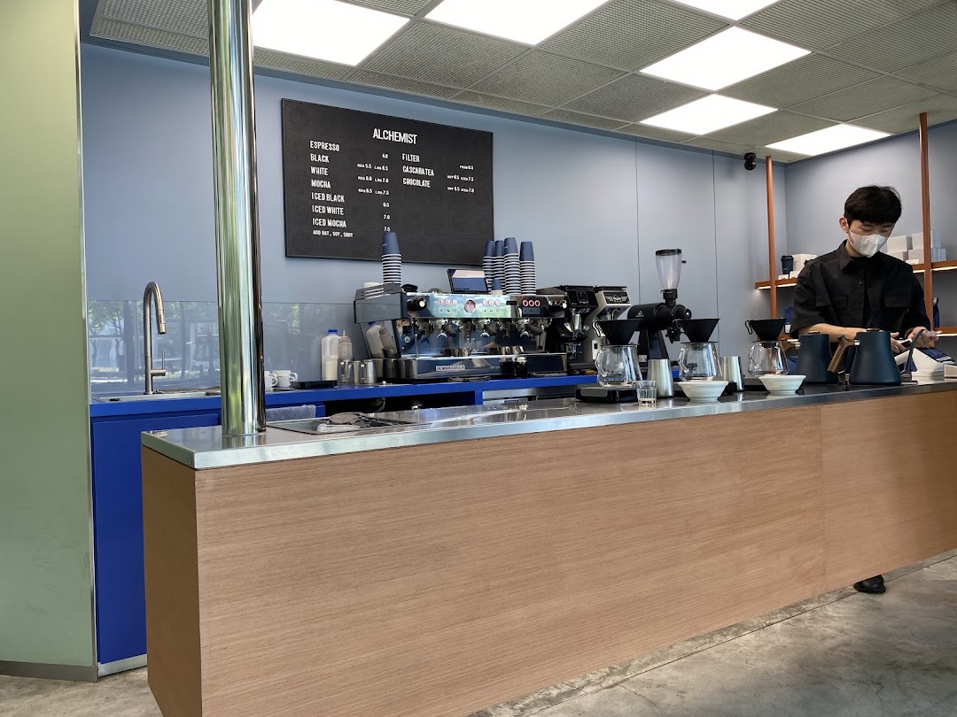 A modern coffee bar with a barista preparing drinks and a menu board displaying offerings.