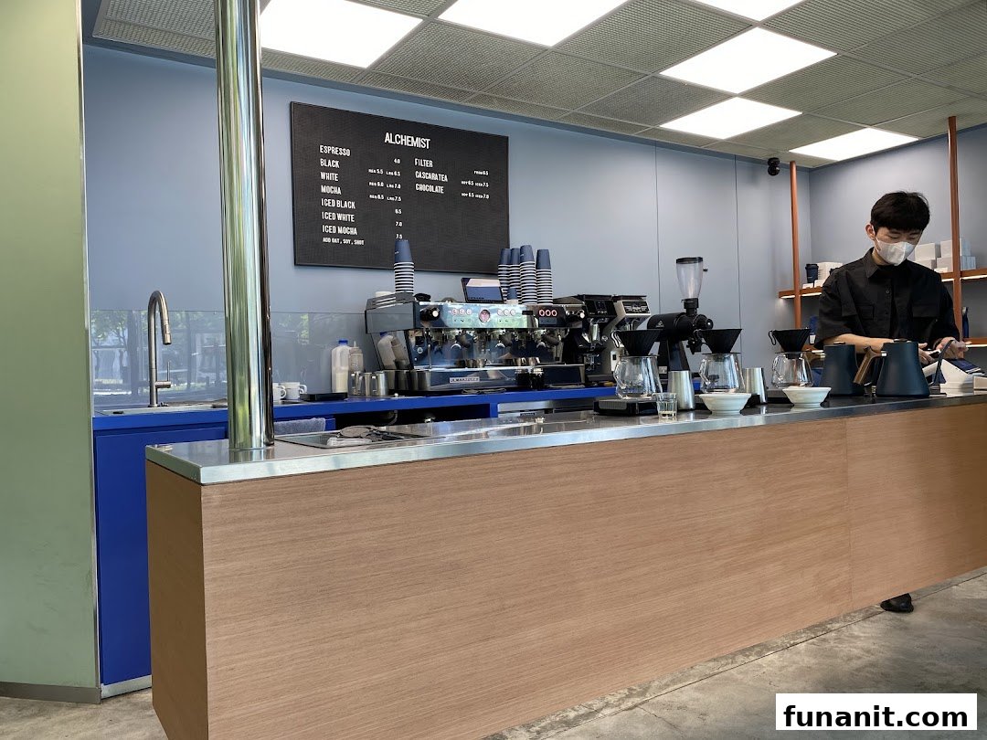 A modern coffee bar with a barista preparing drinks and a menu board displaying offerings.