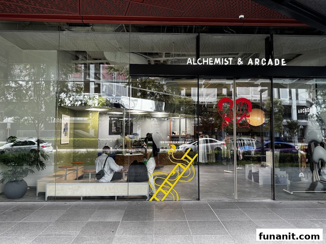 Exterior view of Alchemist & Arcade, showcasing its modern glass facade and inviting interior with a cafe and retail space.