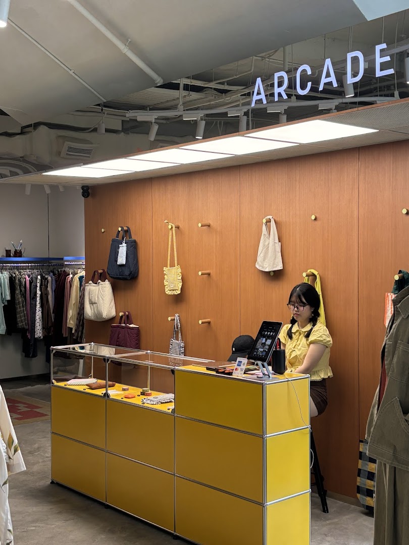Interior view of Alchemist Funan, featuring a bright yellow counter, displayed bags, and clothing racks.