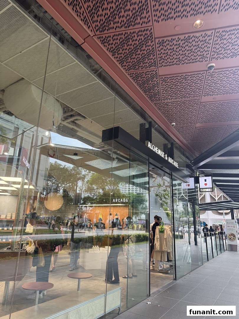 The modern glass facade of Alchemist x Arcade, showcasing its inviting entrance and interior reflections.