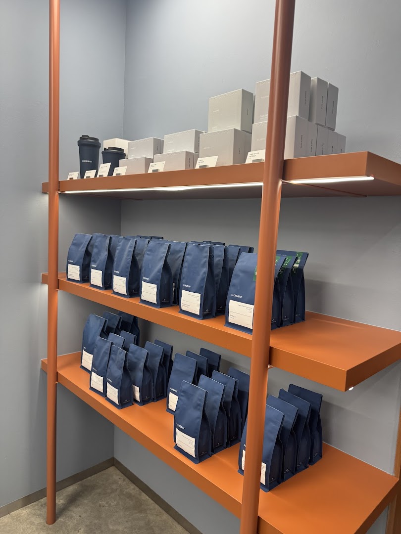 Shelves displaying neatly arranged coffee bags and branded merchandise in a modern retail setting.