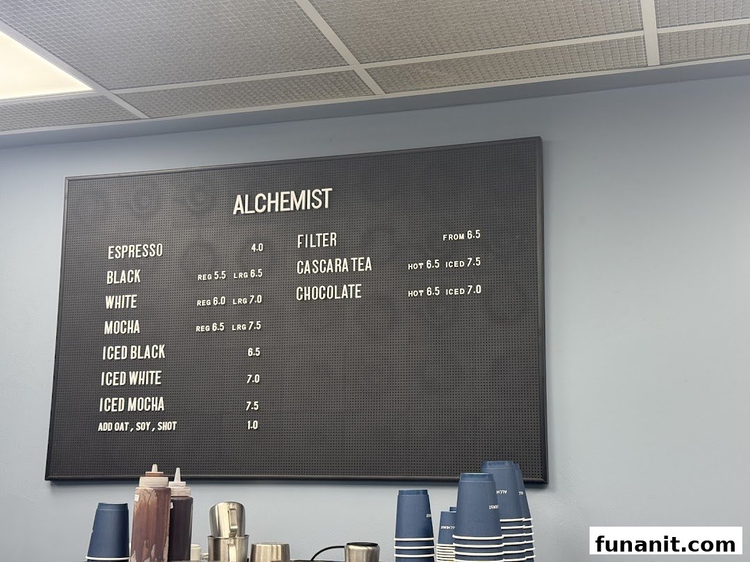 A black menu board displaying coffee and specialty drink options with prices at Alchemist.