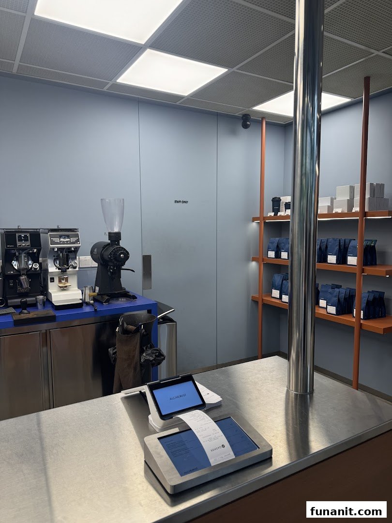 A modern coffee counter with brewing equipment and retail coffee bags on display shelves.