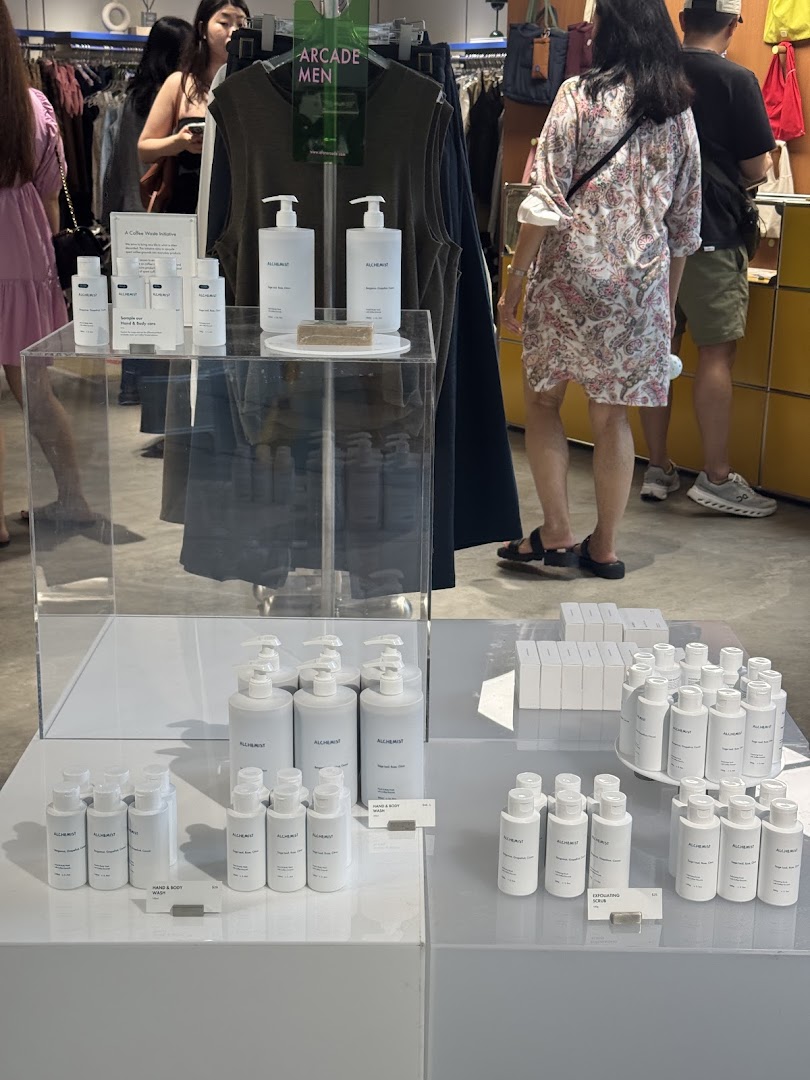 Interior view of Alchemist x Arcade shop, featuring skincare product displays and clothing racks.