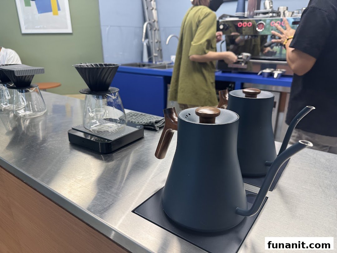 Coffee brewing equipment on a counter with baristas preparing drinks in the background.