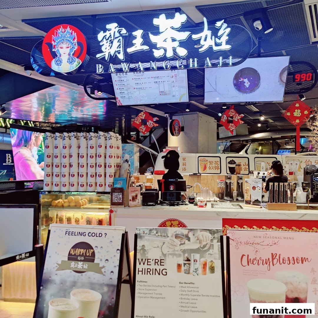 An interior view of a bustling tea shop counter, featuring staff, promotional displays, and branding.