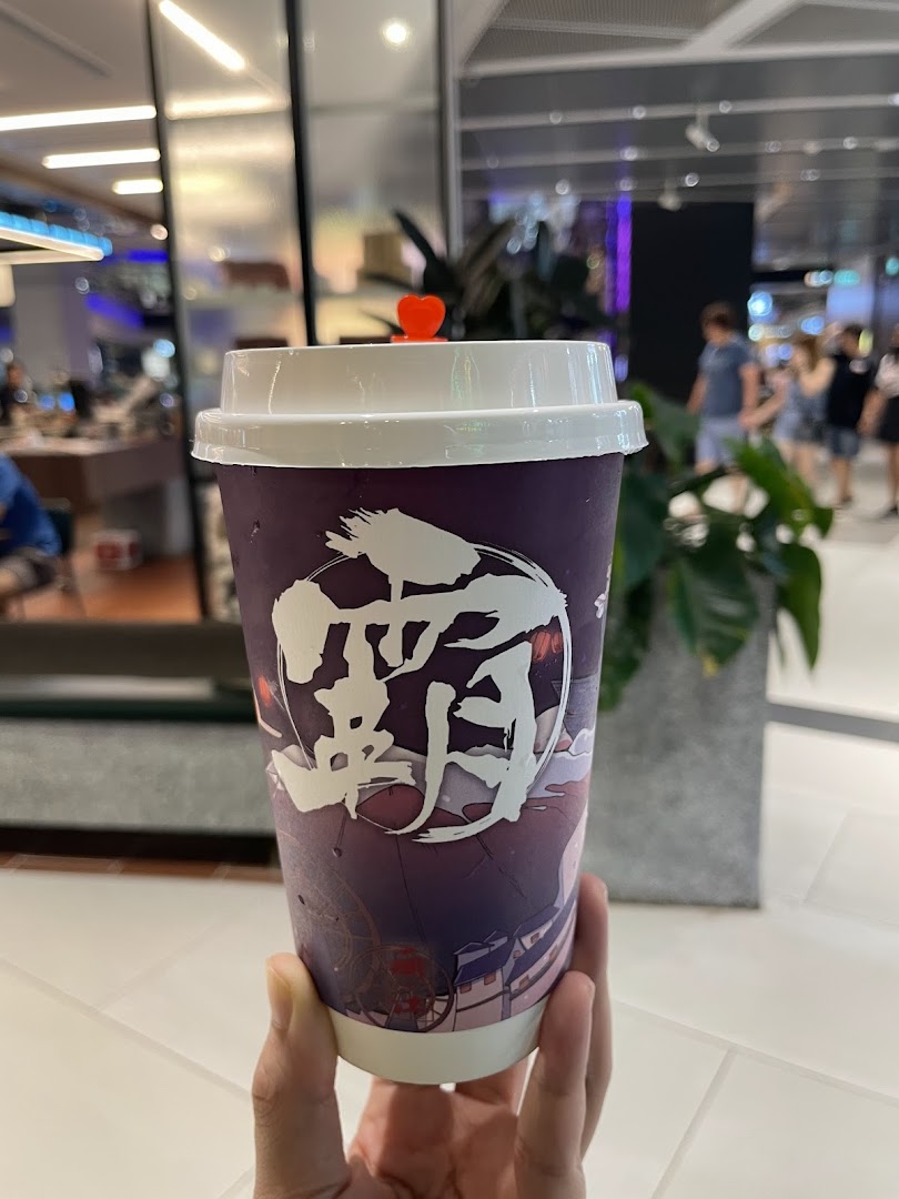 A hand holds a purple beverage cup with Chinese characters, featuring a small red heart on the lid.