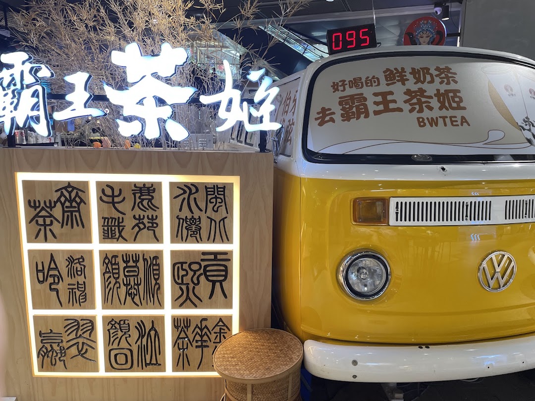 A vibrant shop display featuring a yellow vintage VW van front and a glowing 'BWTEA' sign.