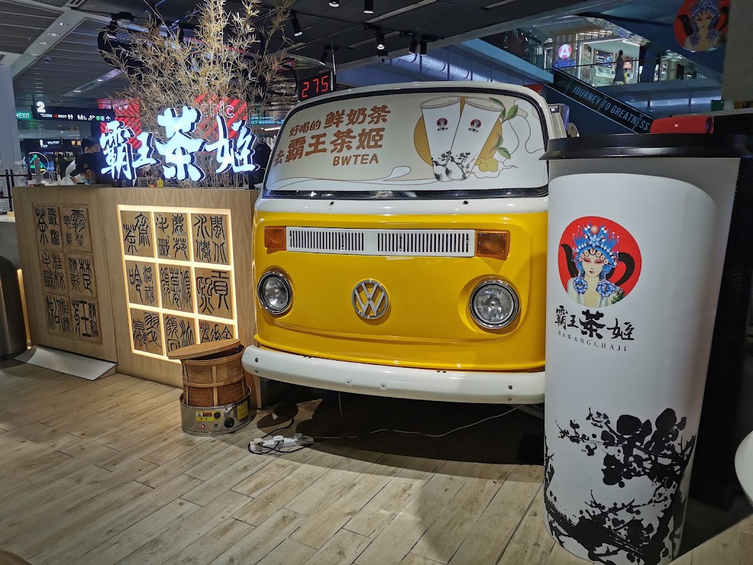 Vibrant interior of Bawangchaji tea shop featuring a yellow vintage van and traditional Chinese decor.