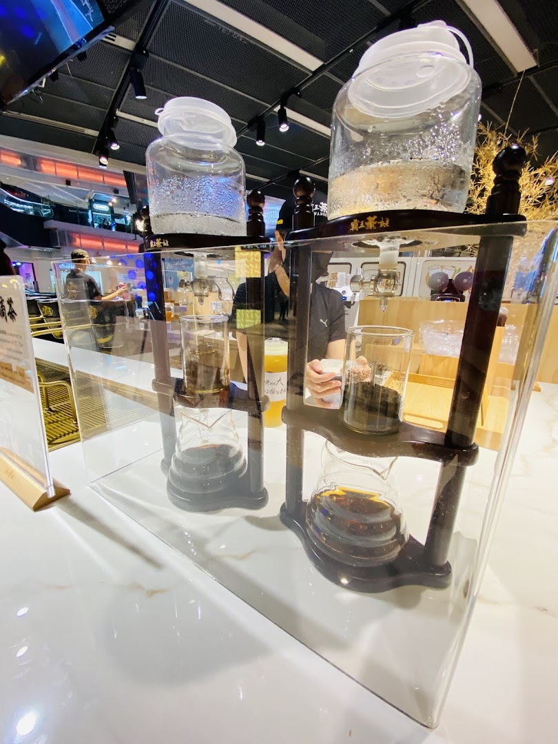 Close-up of two cold brew tea drippers on a white counter inside a modern tea shop.