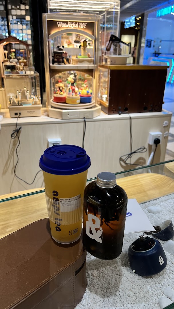 Two beverages, a cup and a bottle, on a counter with decorative display cases in the background.