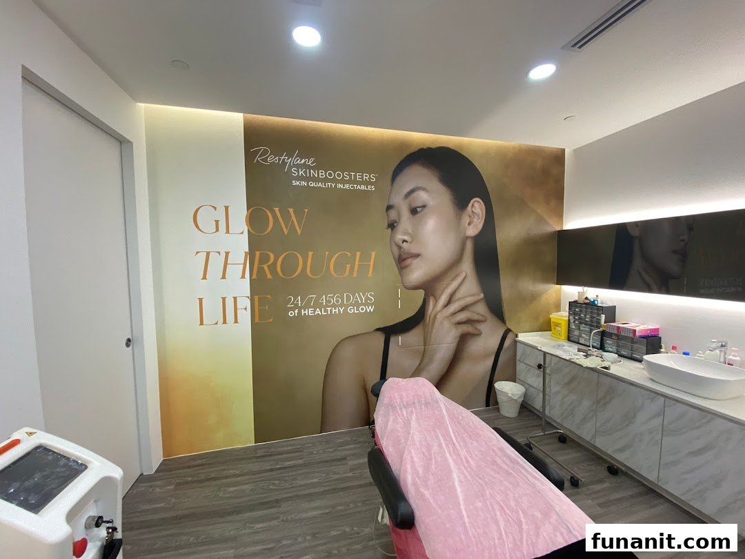An aesthetic clinic treatment room featuring a large 'Glow Through Life' mural and medical equipment.