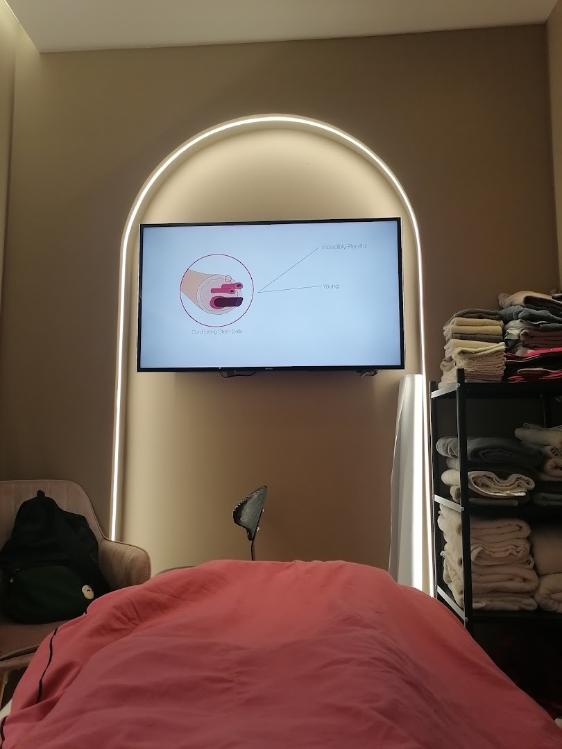An interior view of a medical aesthetics treatment room with a screen displaying scientific information.