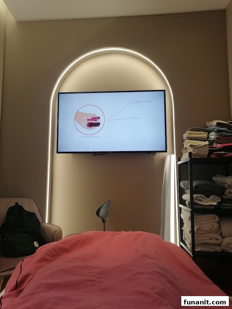 An interior view of a medical aesthetics treatment room with a screen displaying scientific information.