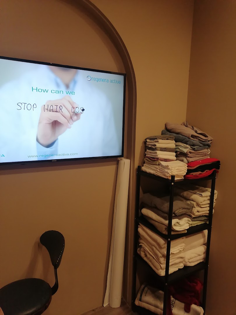 An interior shot of the clinic showing a TV screen displaying 'STOP HAIR LOSS' and a shelf with folded items.