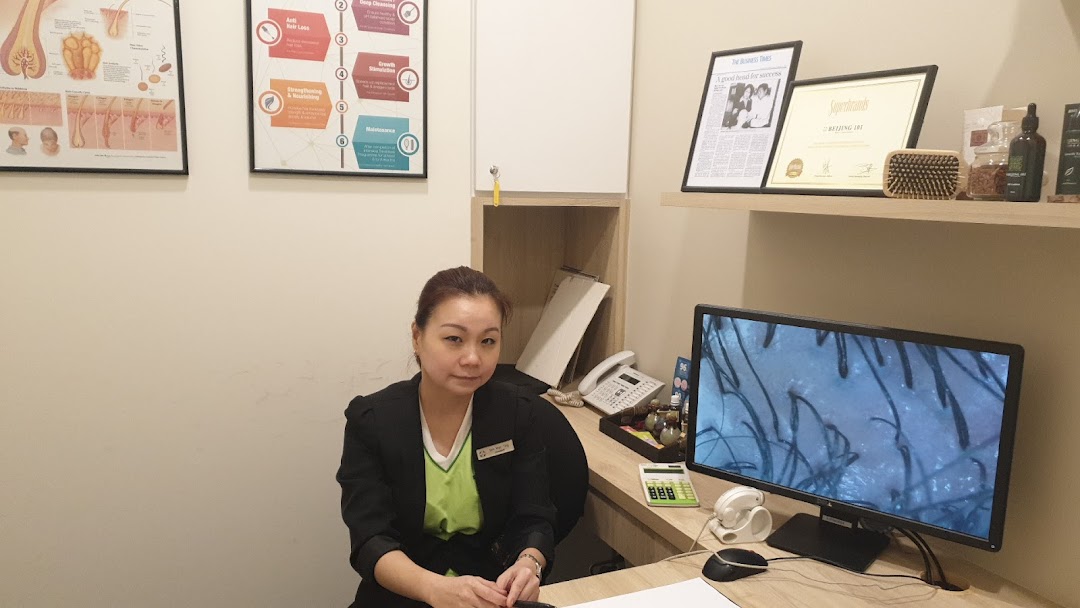 A staff member at Beijing 101 Hair Consultants desk with a magnified scalp image on screen.