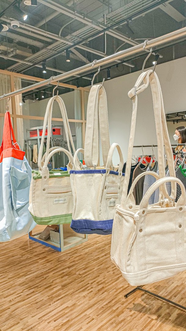 Canvas tote bags in various colors displayed on a rail inside Beyond The Vines Design Store.