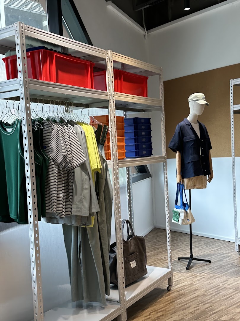 An interior view of a retail store featuring clothing on racks, storage bins, and a mannequin.