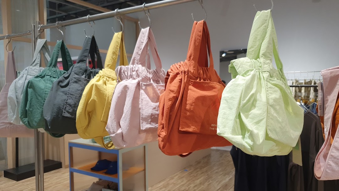 A vibrant display of colorful tote bags from Beyond The Vines hanging on a rail.
