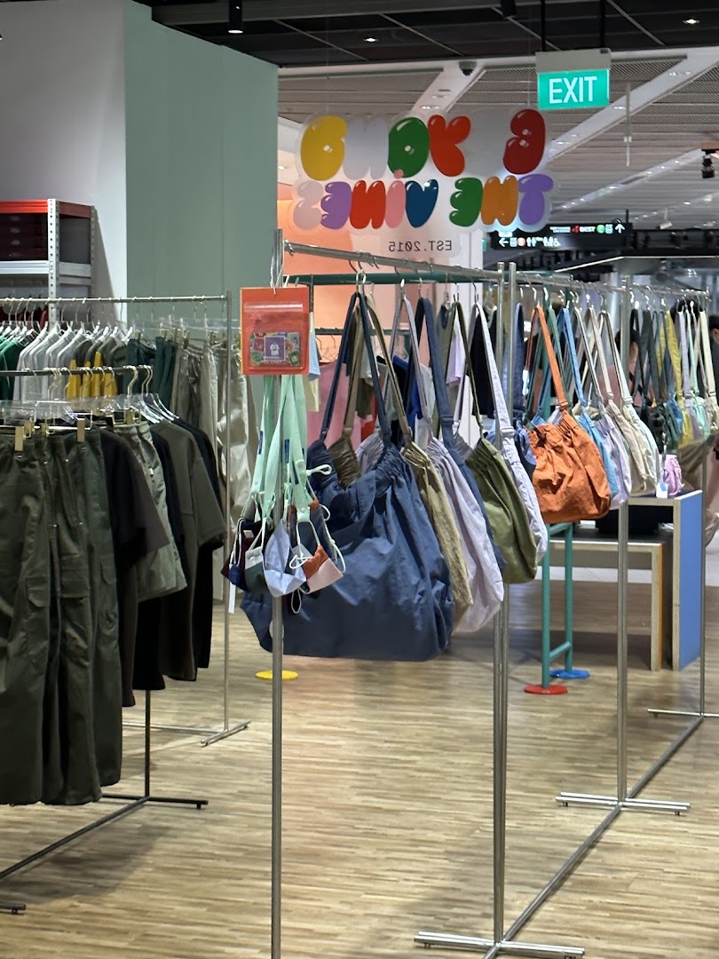 Interior view of Beyond The Vines Design Store, featuring clothing racks and a vibrant display of bags.