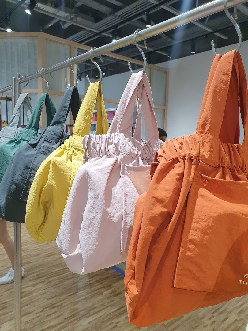 A vibrant display of colorful tote bags hanging on a rail inside Beyond The Vines Design Store.
