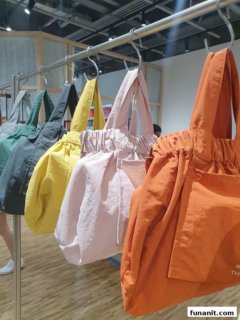 A vibrant display of colorful tote bags hanging on a rail inside Beyond The Vines Design Store.