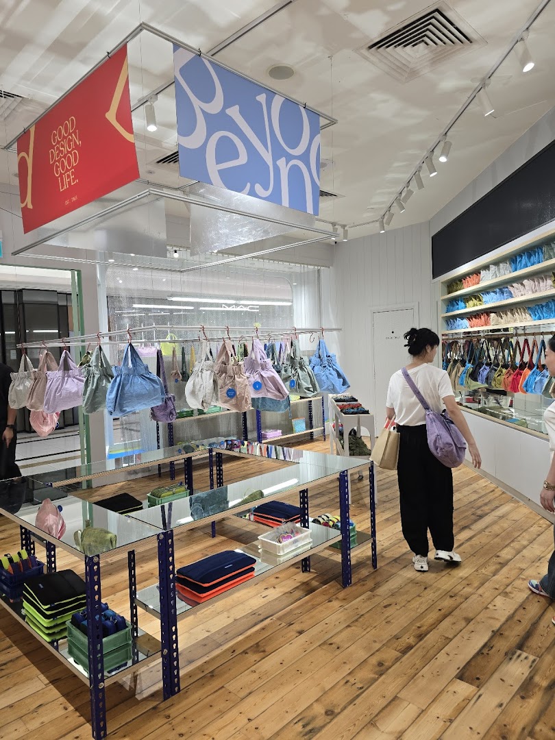 Interior view of Beyond The Vines Design Store, showcasing colorful bags, accessories, and customers browsing.