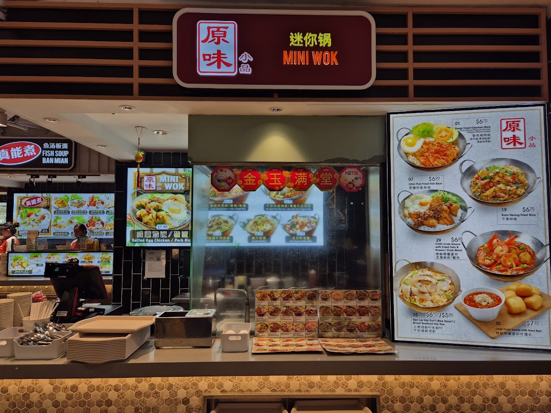 A detailed view of Mini Wok's counter, prominently displaying their menu board with various Asian dishes and prices.