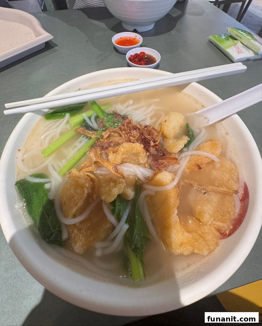 A close-up of a delicious bowl of noodles with crispy toppings and greens.