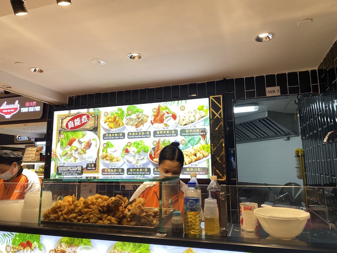 A vibrant digital menu board displaying various fish noodle and dumpling dishes at a food stall.