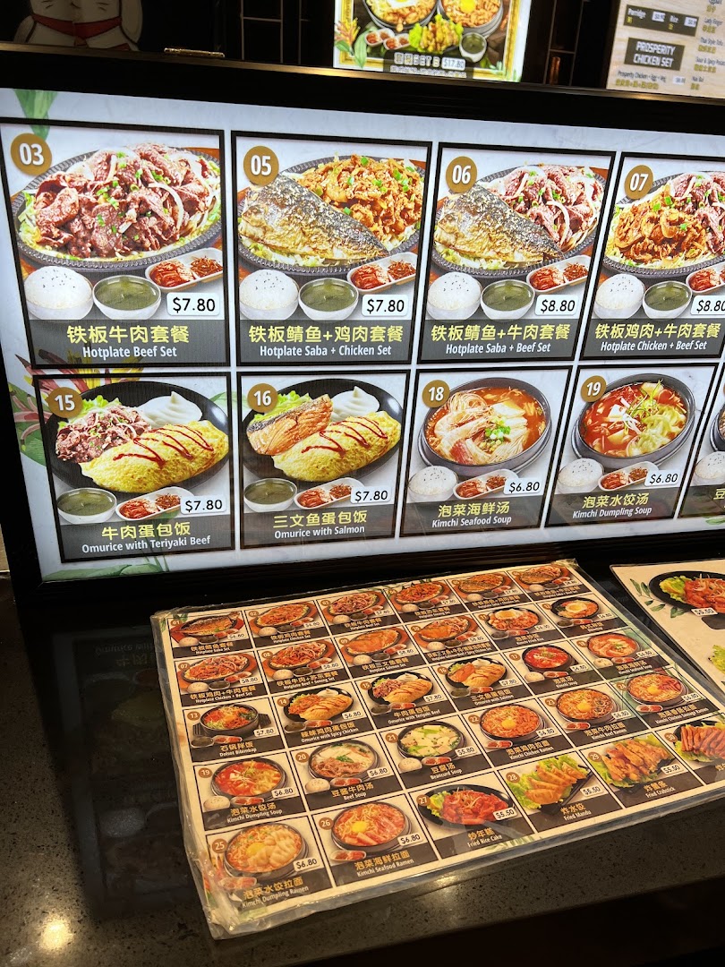 A vibrant menu display and counter menu showcasing various hotplate dishes, omurice, soups, and sides.