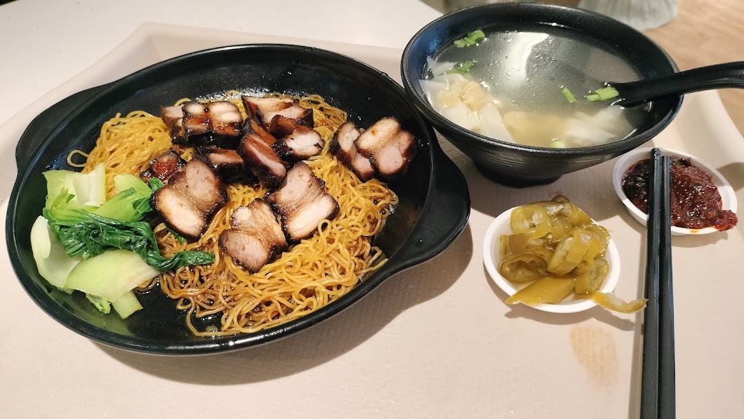 A delicious plate of char siu noodles with bok choy, served with a side of wonton soup and condiments.