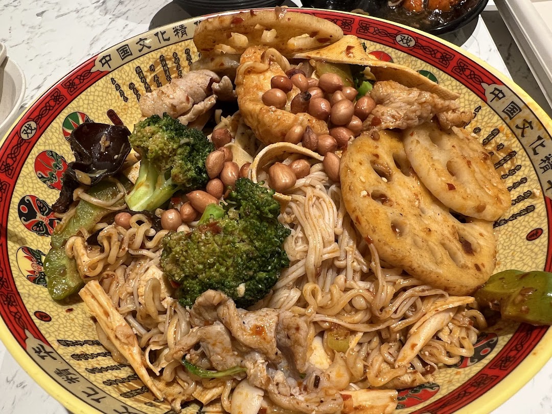 A vibrant, large bowl of Chinese mala xiang guo with noodles, vegetables, and meat.
