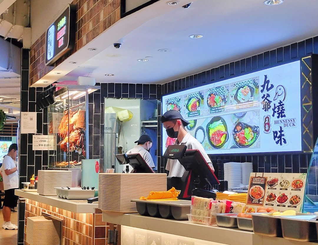 Interior view of a bustling food stall featuring roasted meats, staff, and a digital menu.