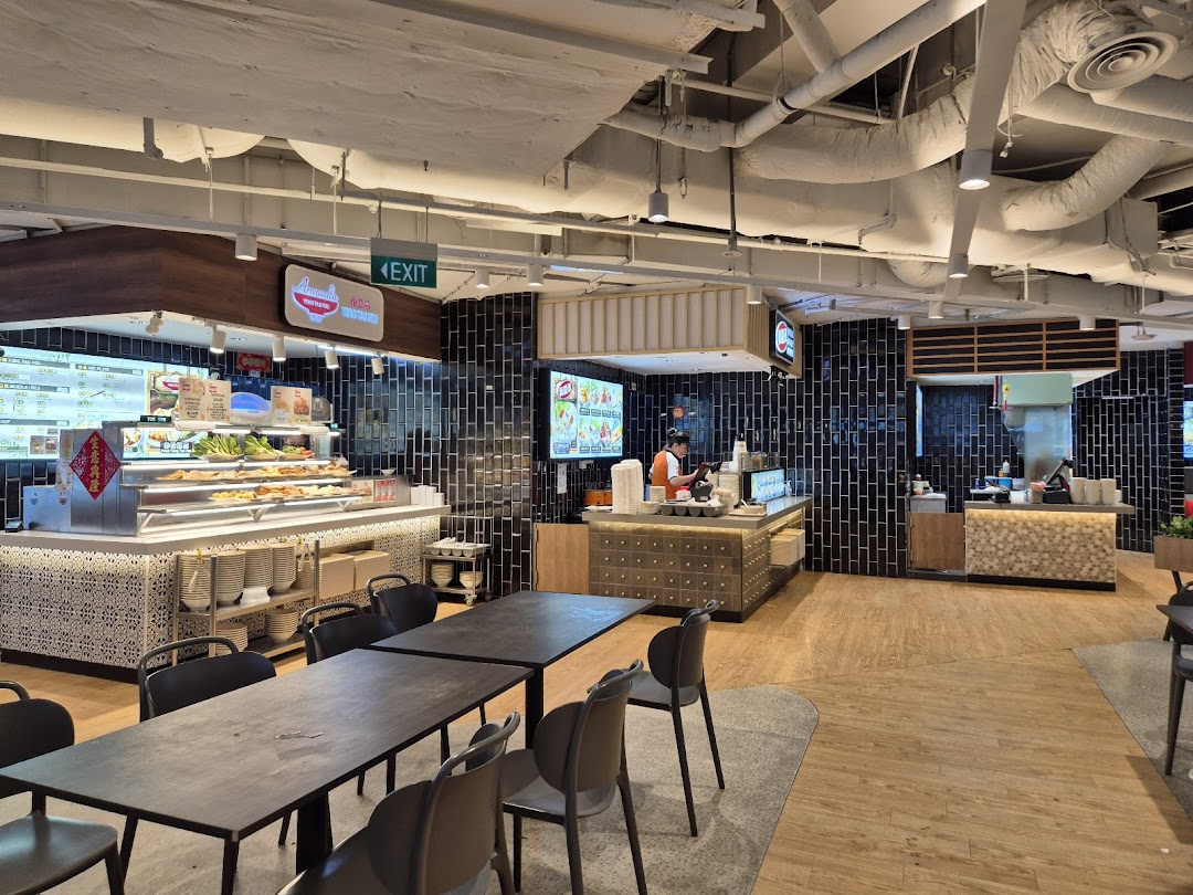 A spacious food court interior with multiple food stalls, dining tables, and a clean, modern design.