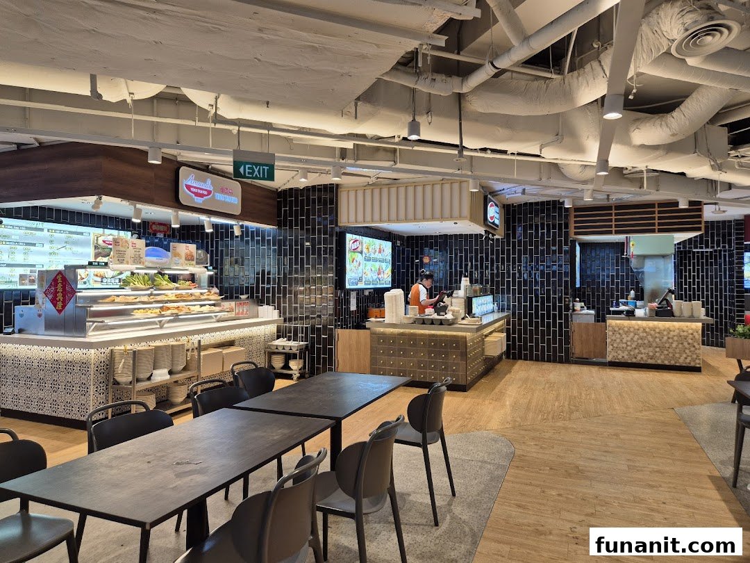 A spacious food court interior with multiple food stalls, dining tables, and a clean, modern design.
