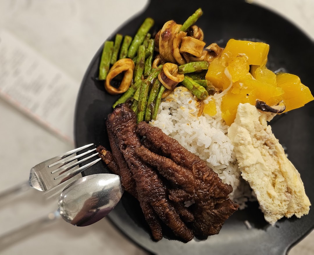 A close-up of a hearty meal featuring rice, chicken feet, squid, green beans, and pumpkin.
