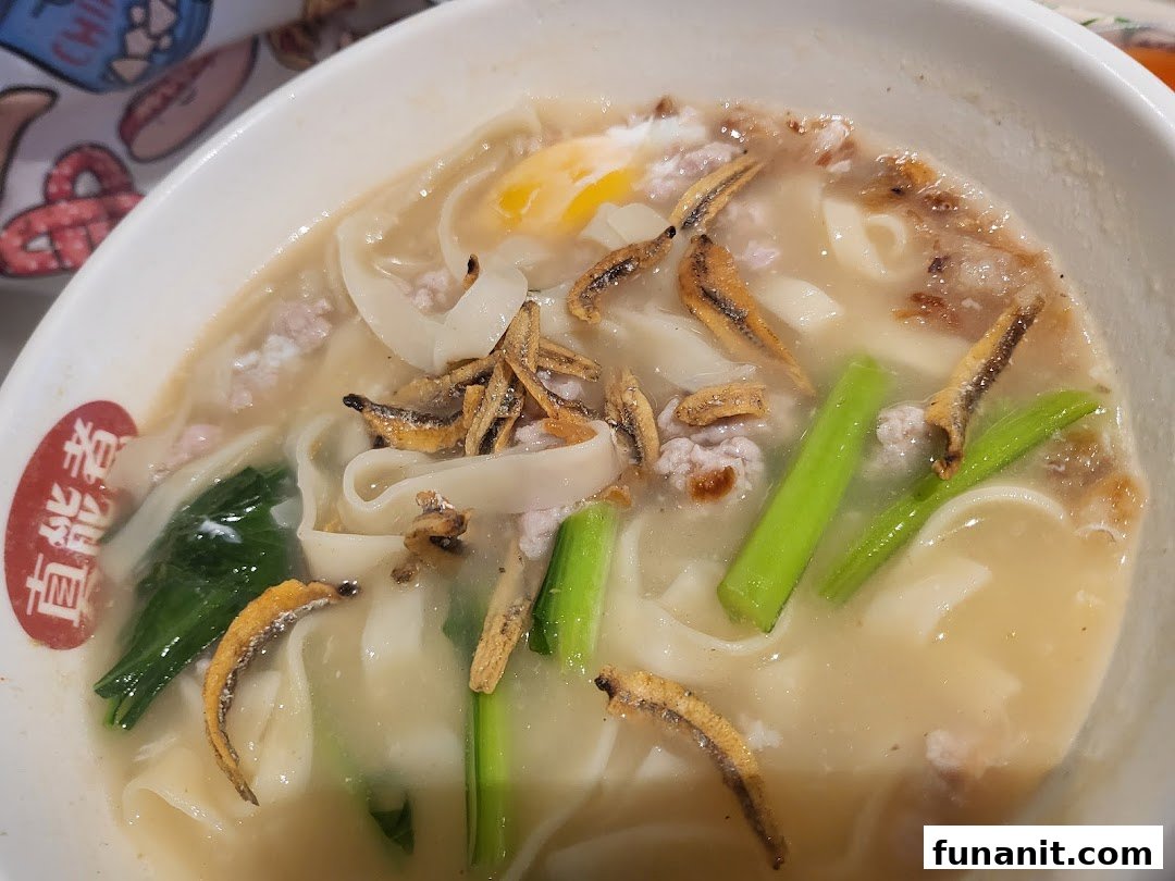 A hearty bowl of noodles with minced meat, crispy anchovies, vegetables, and a poached egg.