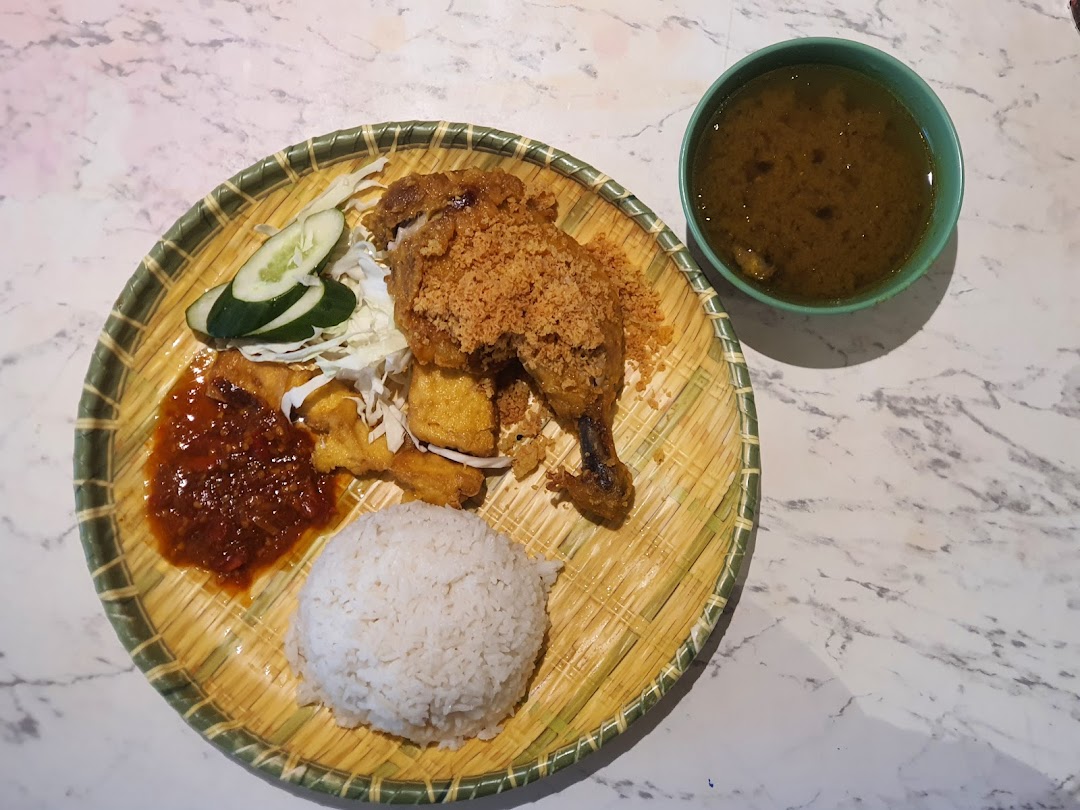 A delicious plate of fried chicken with rice, sambal, and soup, served on a traditional woven plate.