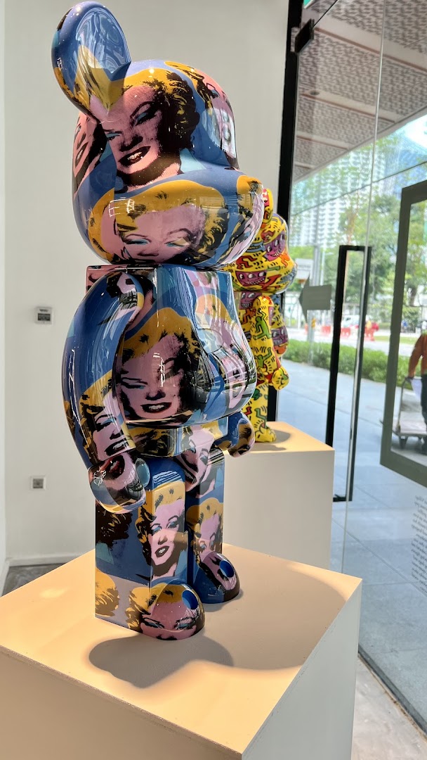 A large, vibrant Bearbrick art toy featuring Andy Warhol's Marilyn Monroe pop art design on display.