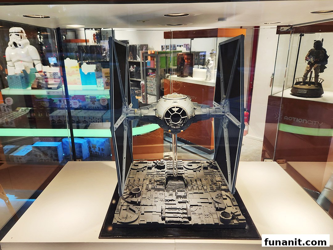 A detailed Star Wars TIE Fighter model is prominently displayed in a shop, surrounded by other pop culture collectibles.