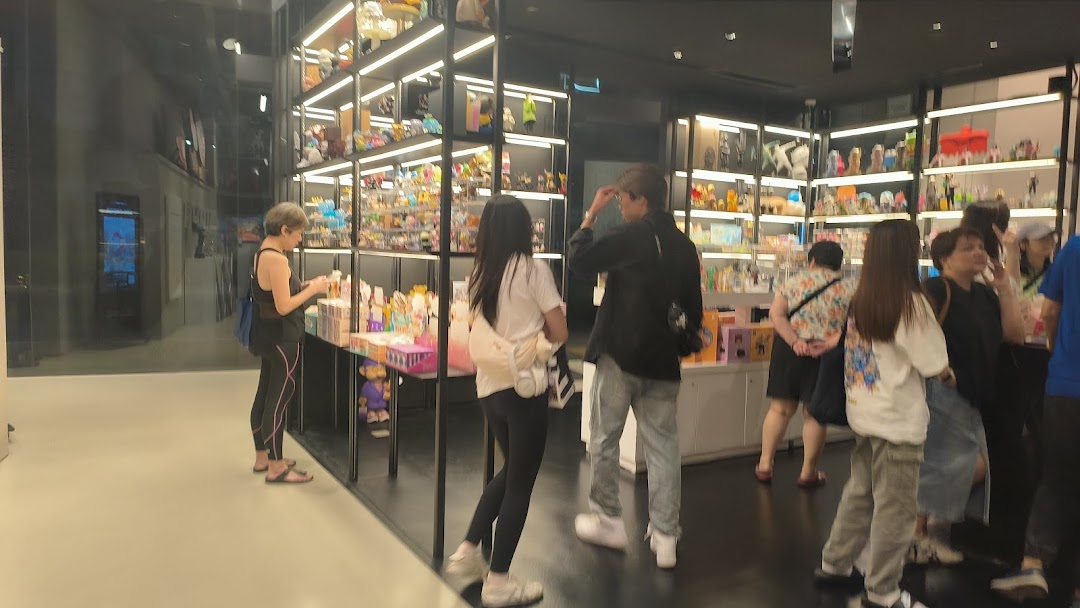 Customers browse a wide array of collectible art toys and figures displayed on brightly lit shelves.