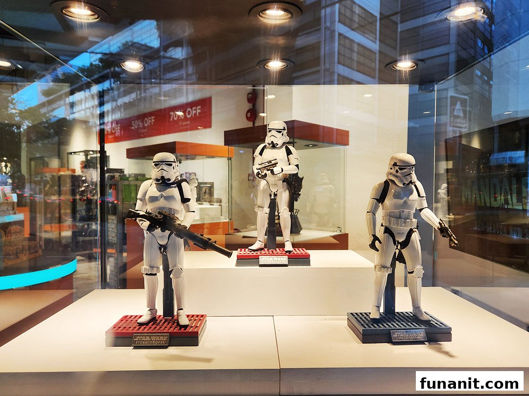 Three Star Wars Stormtrooper figures displayed prominently in a retail shop's front window.