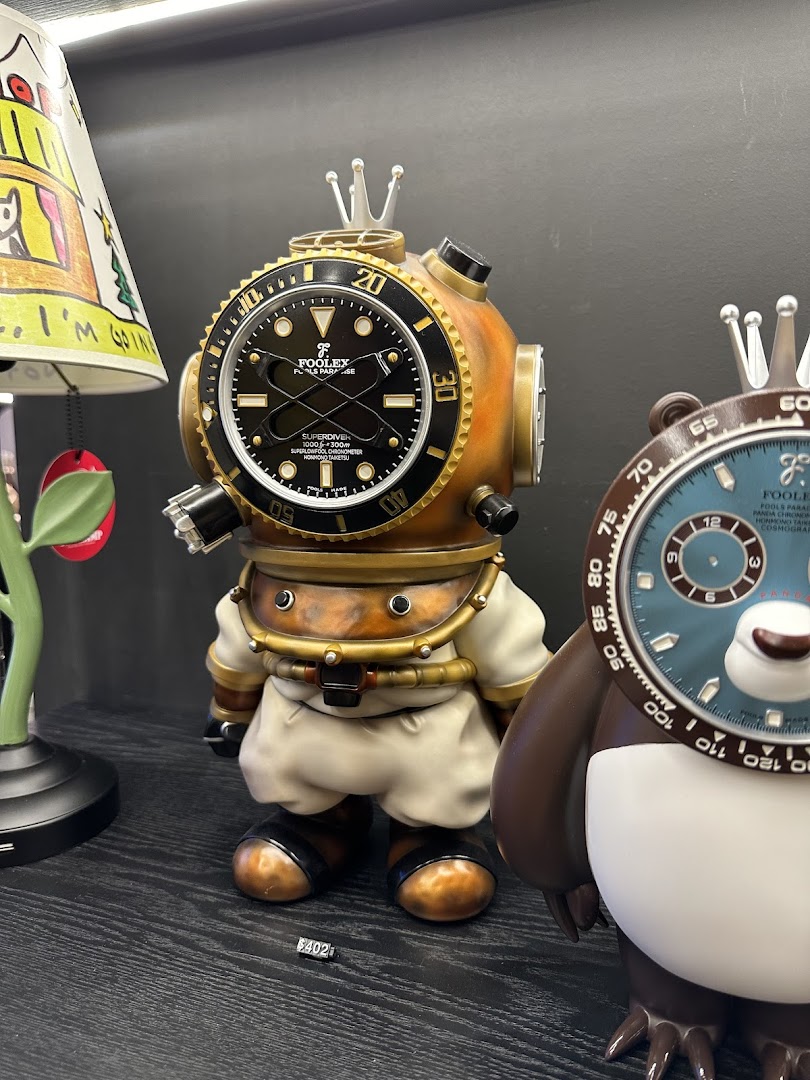 Close-up of unique collectible art toys, including a diver-themed figure with a watch face, displayed in a shop.