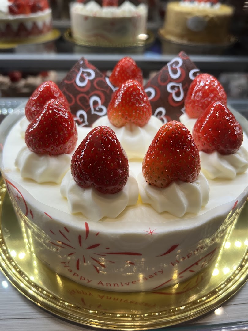 A delightful strawberry cake with whipped cream and chocolate decorations, perfect for celebrations.