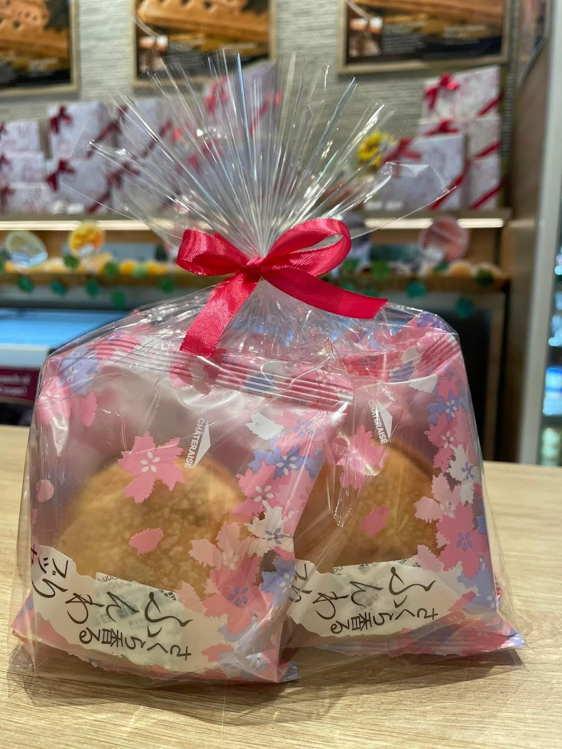 A beautifully packaged gift set of Châteraisé pastries with cherry blossom design and a pink bow.