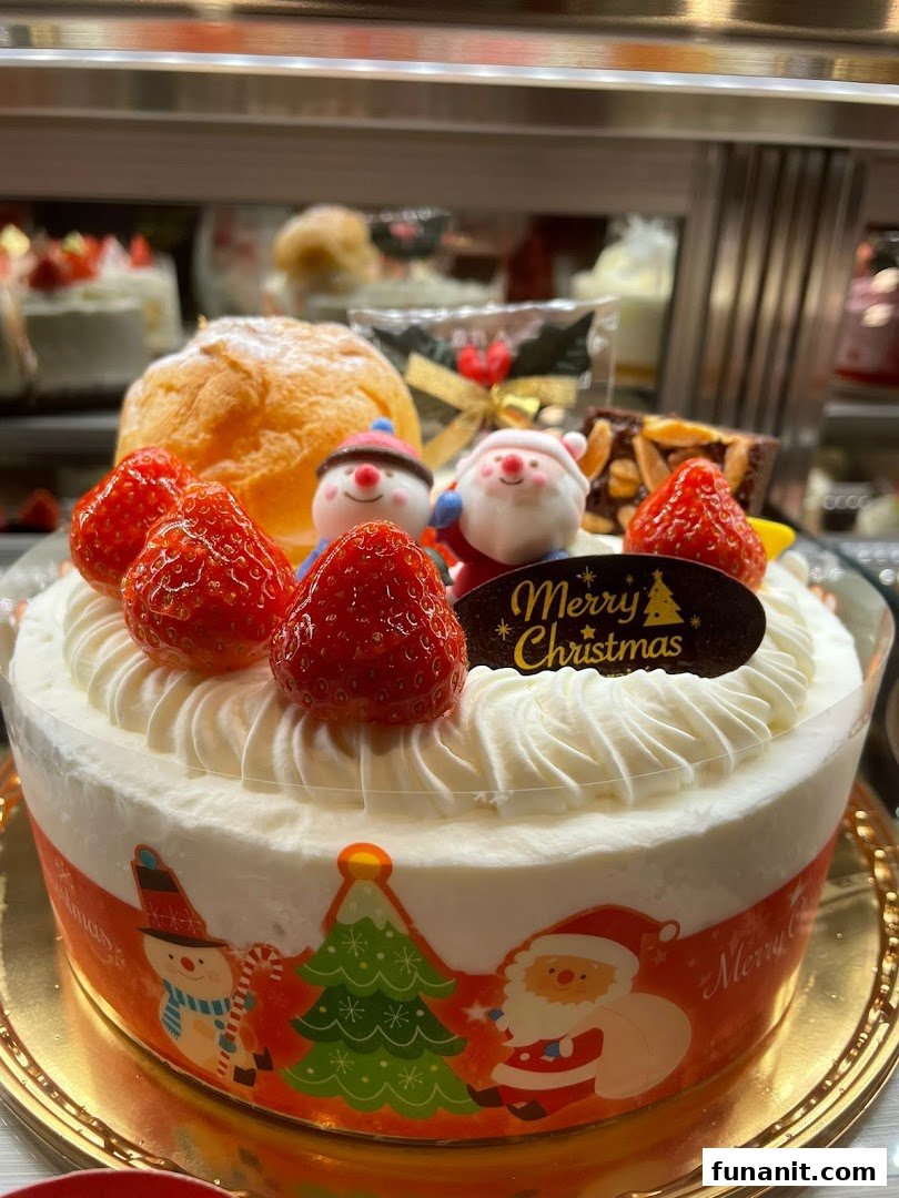 A festive Christmas cake adorned with fresh strawberries, whipped cream, and charming holiday figurines.