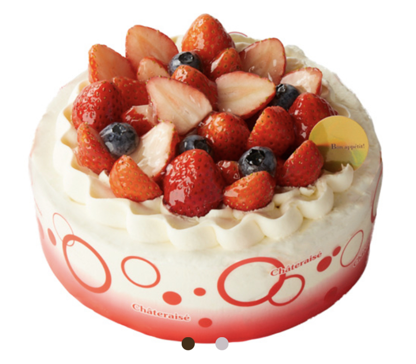 A vibrant Châteraisé cake adorned with fresh strawberries and blueberries, topped with cream.